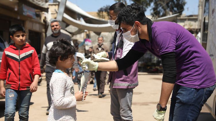 Ein Mitarbeiter einer nicht staatlichen Hilfsorganisation misst bei einem Kind in der Provinz Idlib die Temperatur. 