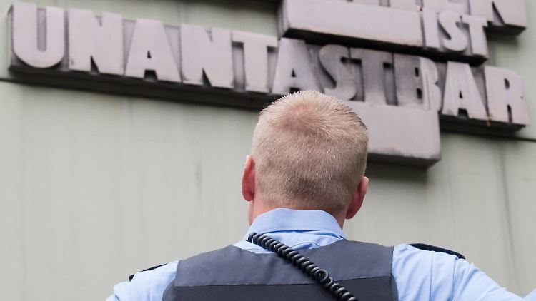 Ein Polizist liest den Artikel 1 des Grundgesetzes an der Fassade des Frankfurter Oberlandesgerichts.