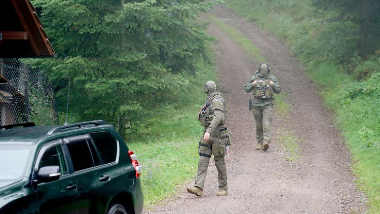 Zwei maskierte Polizisten schreiten das Waldgebiet bei Oppenau ab.