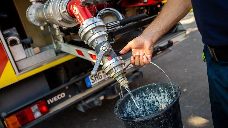 Einsatzkräfte der Freiwilligen Feuerwehr Lauenau zapfen Löschwasser aus dem Tank eines ihrer Einsatzfahrzeuge.