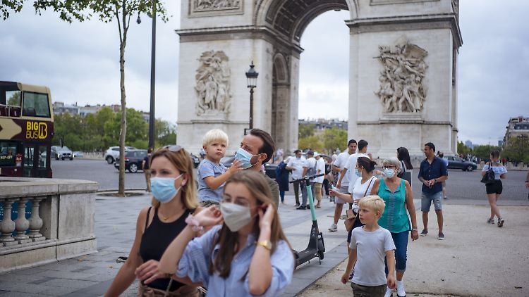 Touristen tragen Schutzmasken beim Bummel über den Pariser Prachtboulevard.