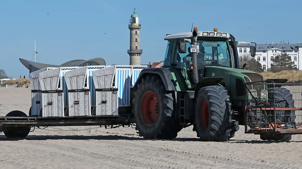 Mit-einem-Traktor-werden-die-Strandkoerbe-in-Richtung-Wasser-gebracht