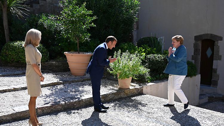 Macron unter der mediterraner Sonne zwischen Gattin und Kanzlerin (r.).