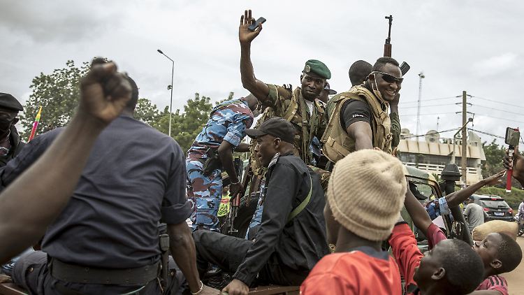 Menschen jubeln, als Sicherheitskräfte nach dem Putsch durch die Straßen der Hauptstadt Bamako fahren.