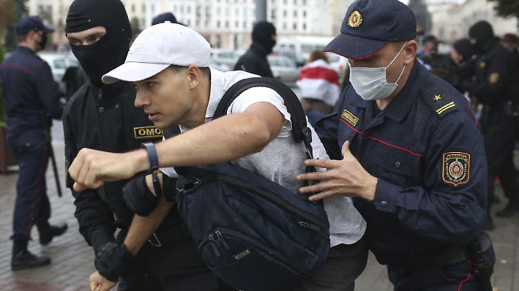 Belarussische Polizisten halten einen festgenommenen Demonstranten fest.