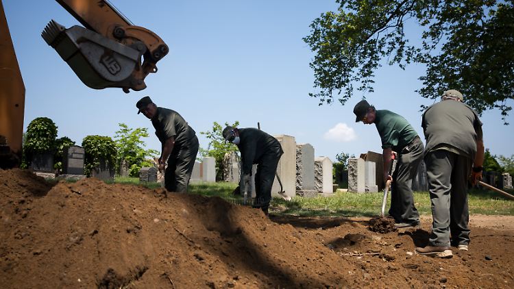 Mitarbeiter eines New Yorker Friedhofs arbeiten während der Corona-Pandemie an einem Grab.