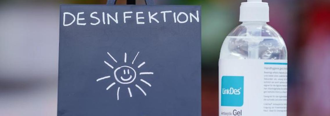 Ein Schild mit der Aufschrift "Desinfektion" und eine Flasche mit Desinfektionsmittel. Foto: Uwe Anspach/dpa/Archivbild