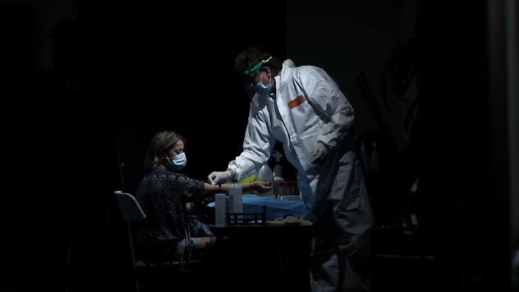 Ein medizinischer Mitarbeiter nimmt einer Frau in einem Auditorium in Madrid Blut ab.
