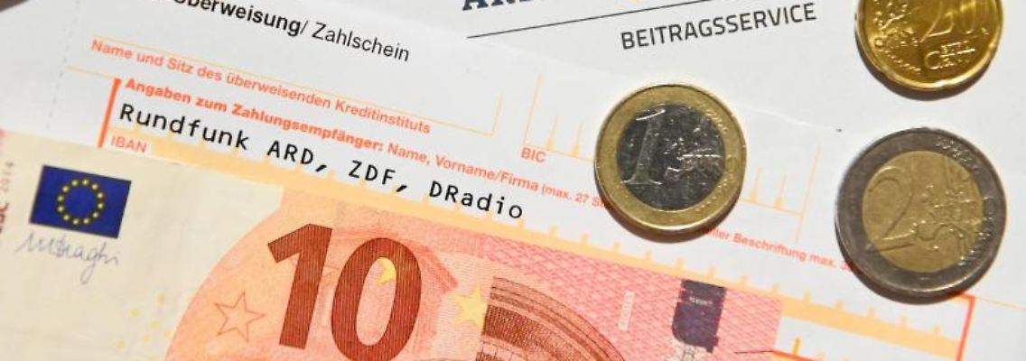 Auf einem Tisch liegt ein Anschreiben und Überweisungsträger für die Rundfunkgebühren, sowie der Betrag von 18 Euro und 36 Cent. Foto: Nicolas Armer/dpa/Archivbild