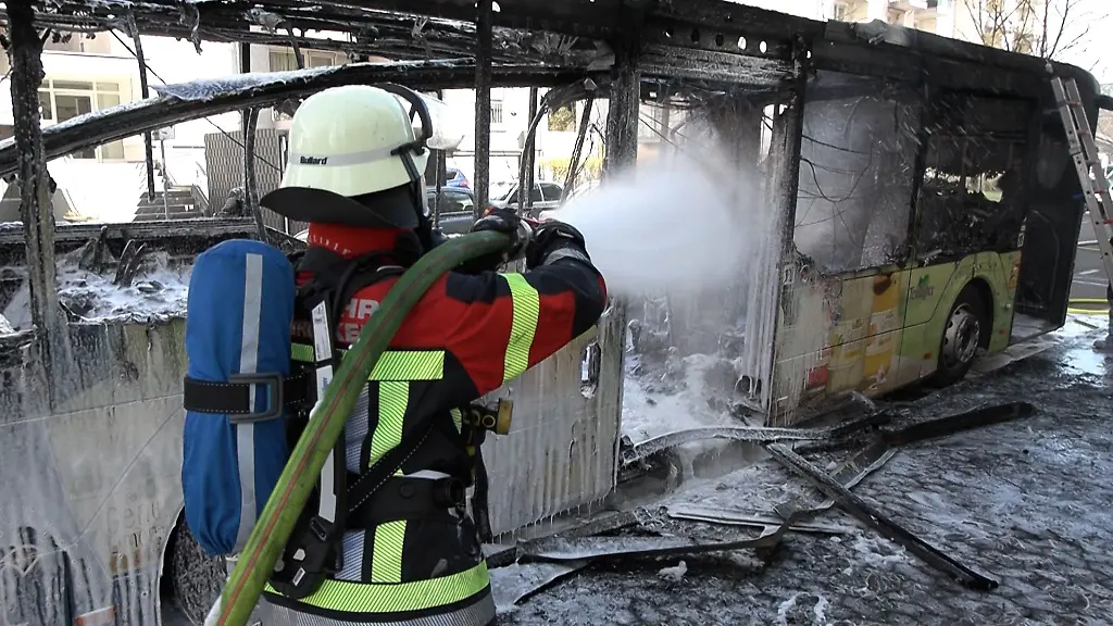 Ein-Feuerwehrmann-loescht-einen-in-Brand-geratenen-Bus