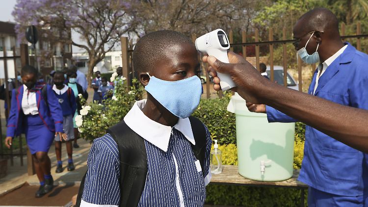Einem Kind in Simbabwe wird vor dem Schuleintritt die Temperatur gemessen. 