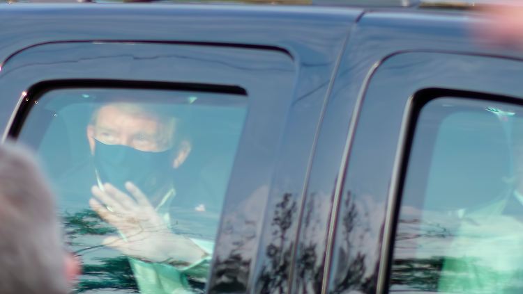Der erkrankte US-Präsident grüßt  aus dem Auto heraus seine Anhänger vor dem Walter Reed National Military Medical Center in Bethesda.