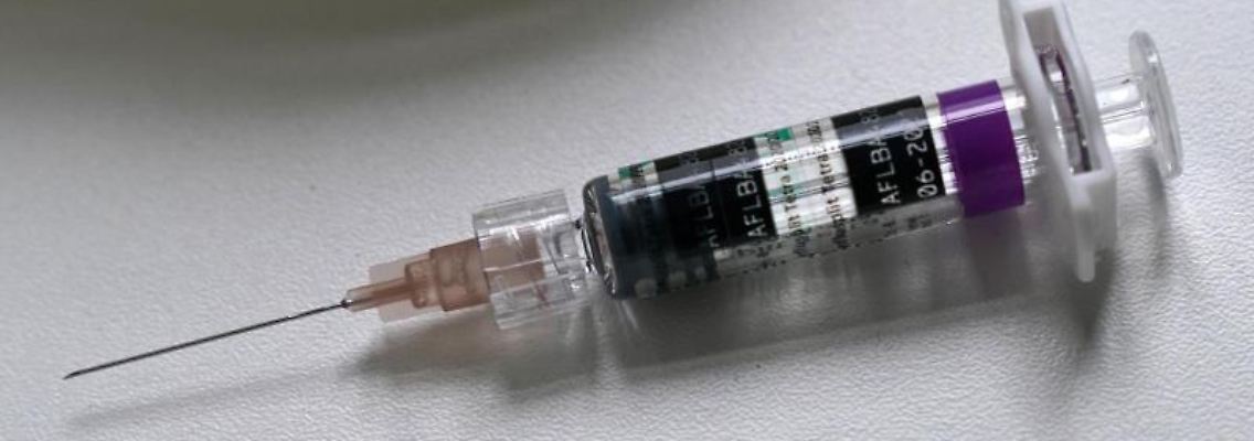 Eine Spritze mit einer Einmal-Injektions-Kanüle liegt nach einer Impfung gegen Grippe auf einem Tisch.jpg