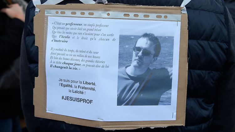 Ein Demonstrant trägt ein Schild mit dem Foto von Samuel Paty.