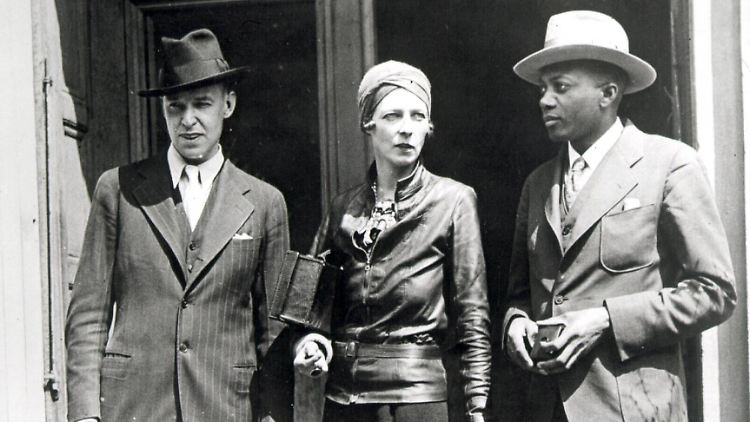 Nancy Cunard mit dem Maler John Banting (l.) und Taylor Gordon, einem Schriftsteller, vor dem Hotel in Harlem, das sie vor die Tür gesetzt hat.