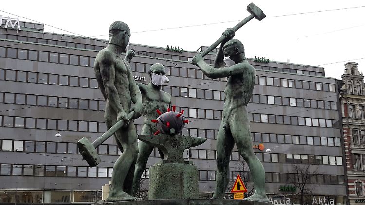 Eine Coronavirus-Nachbildung liegt auf dem Amboss der Bronzestatue "Drei Schmiede" in Helsinki.