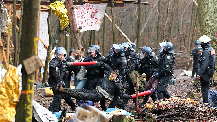 Polizisten tragen drei Aktivisten, die ihre Arme in Metallrohre gesteckt und sich so miteinander verbunden haben, aus dem Camp im Dannenröder Forst.