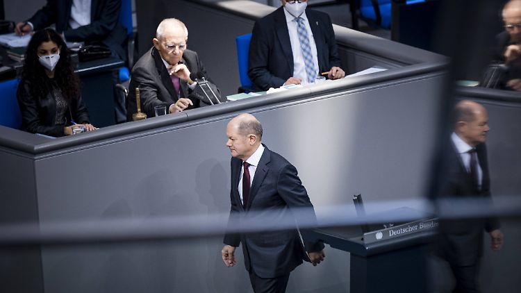 Scholz bekam einen Mund-Nasen-Schutz von einer Mitarbeiterin - und ging weiter, ohne ihn aufzusetzen.