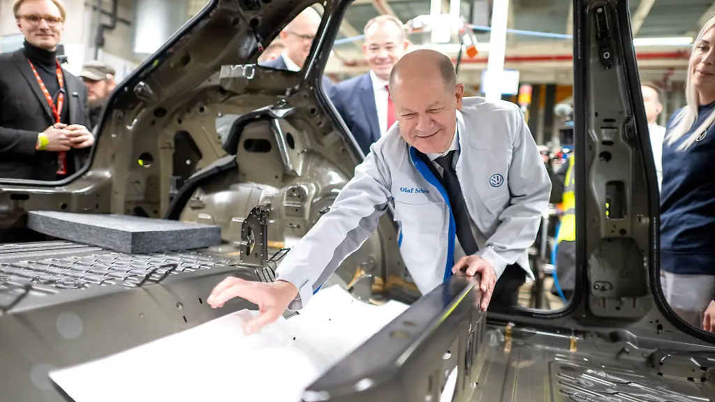 Bei-seinem-Besuch-im-Emder-VW-Werk-hilft-Bundeskanzler-Olaf-Scholz-SPD-beim-Einbau-einer-Daemmmatte
