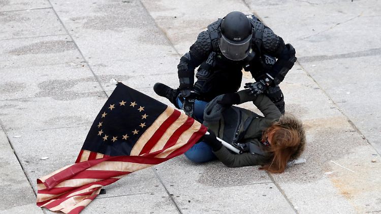 Ein Polizist hält einen Trump-Anhänger fest, als der Mob das Kapitol in Washington stürmt.