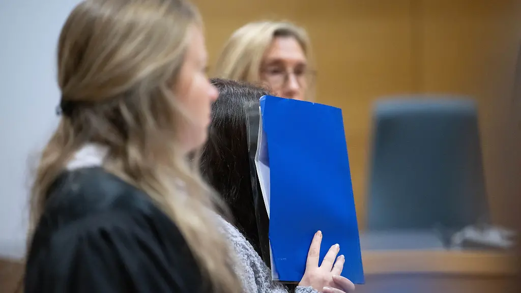 Eine-wegen-Mordes-durch-Unterlassung-angeklagte-Frau-Mitte-nimmt-mit-ihren-Anwaeltinnen-Lena-Bretz-links-und-Andrea-Yvonne-Combe-am-Auftakt-eines-Prozesses-im-Landgericht-Heidelberg-teil