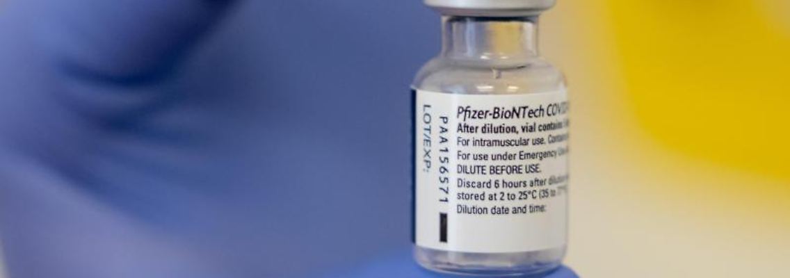 Eine Frau zeigt in einer Impfstelle eine Ampulle mit dem Impfstoff von Biontech/Pfizer.jpg