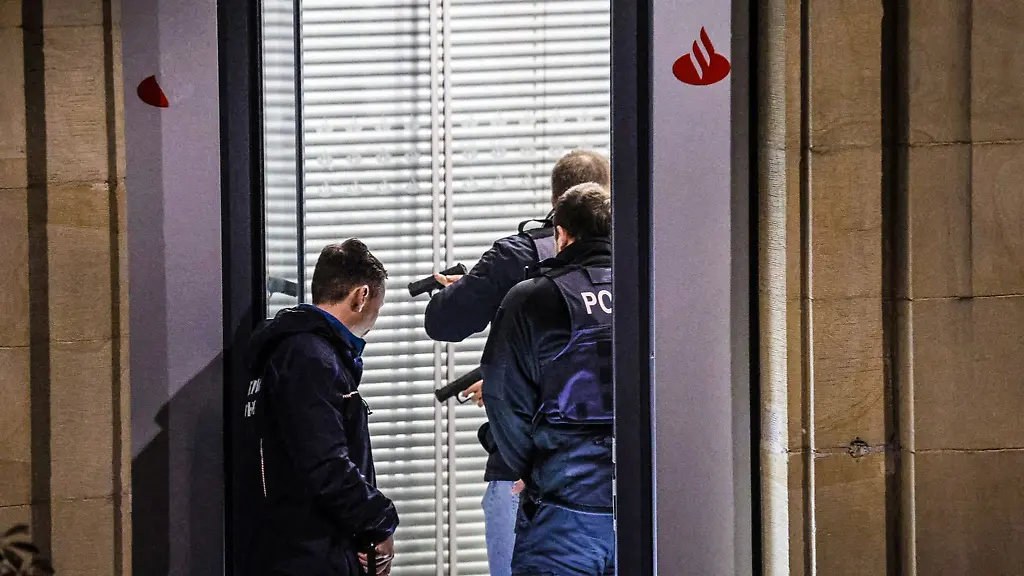 Mit-gezueckten-Waffen-stehen-Polizisten-nach-der-Sprengung-eines-Geldautomaten-in-einer-Bank