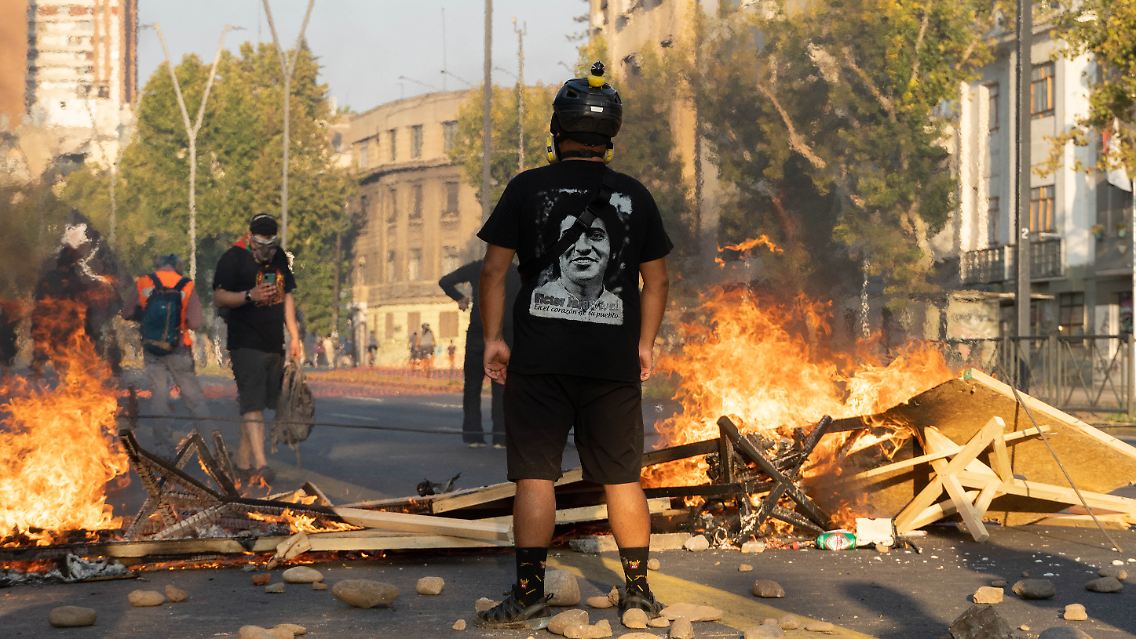 Ein Demonstrant steht vor einer brennenden Blockade.
