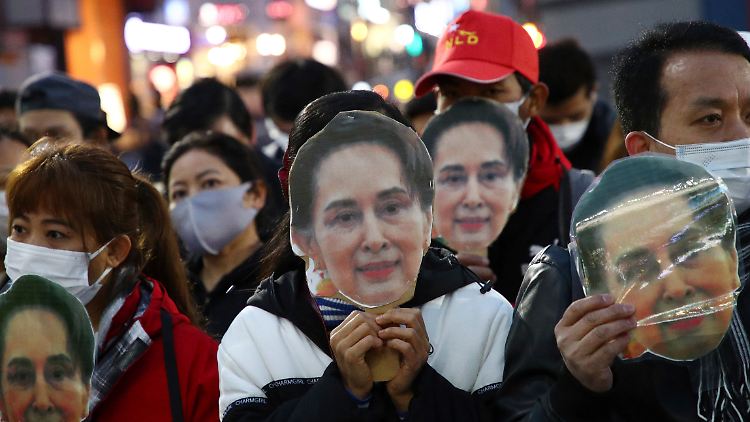 Anhänger der entmachteten De-facto-Regierungschefin Aung San Suu Kyi halten sich ihr Foto vors Gesicht.