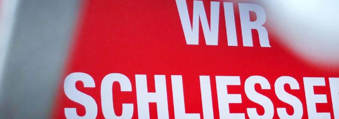 Der Schriftzug "Wir schließen!" steht hinter einem Rollgitter an einem geschlossenen Geschäft. Foto: Martin Gerten/dpa