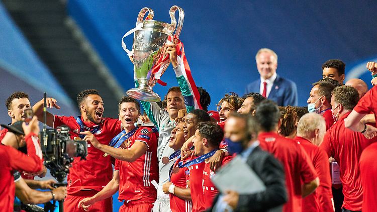 Vorne feiert die Mannschaft, im Hintergrund genießt Rummenigge den Erfolg des FC Bayern.