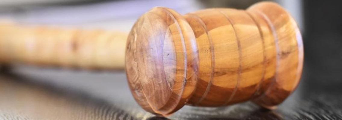 Ein Richterhammer aus Holz auf einer Richterbank. Foto: Uli Deck/dpa/Symbolbild