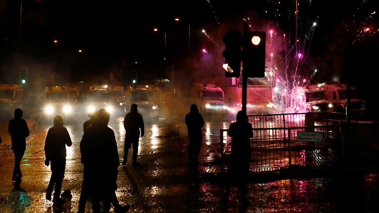 Ein Feuerwerkskörper explodiert vor Polizeifahrzeugen in Belfast.