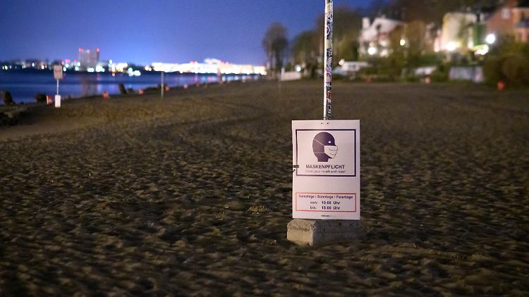 Am menschenleeren Elbstrand in Hamburg-Övelgönne weist ein Schild auf eine tagsüber geltende Maskenpflicht hin.