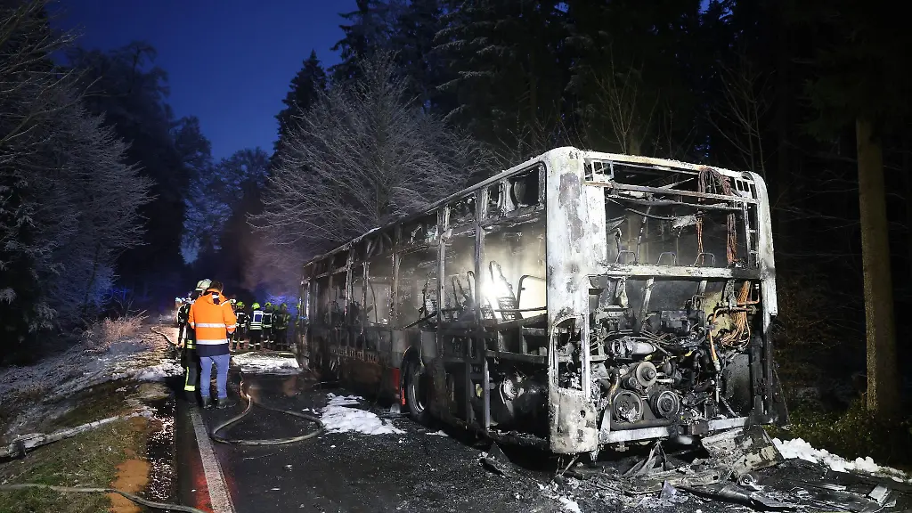 Einsatzkraefte-stehen-neben-einem-ausgebrannten-Bus-Der-Linienbus-ist-im-Kreis-Biberach-in-Brand-geraten