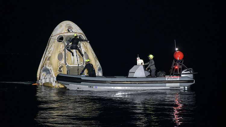 Helfer befestigen ein Seil an der "Crew Dragon" - Kapsel, mit der die Astronauten zuvor im Golf von Mexiko gelandet waren.
