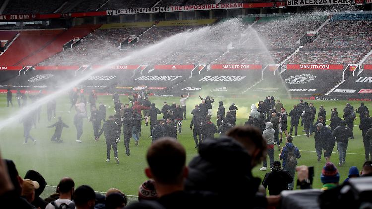 Die Fans von Manchester United auf dem Rasen in Old Trafford.