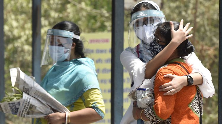 Eine Angehörige eines Corona-Todesopfers im indischen Noida bekommt Trost zugesprochen.