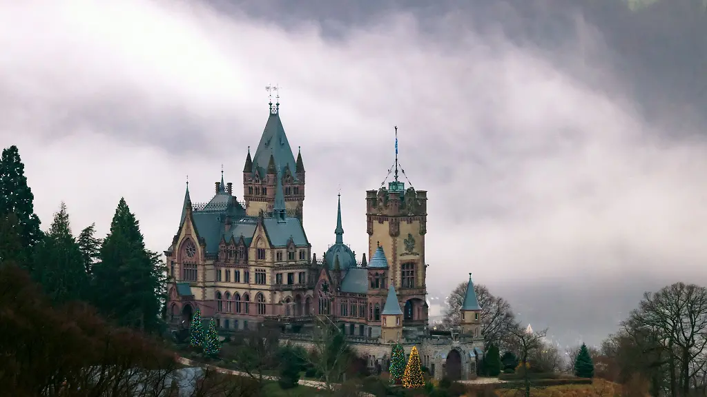 Weihnachtsbaeume-leuchten-an-der-im-Nebel-liegenden-Drachenburg