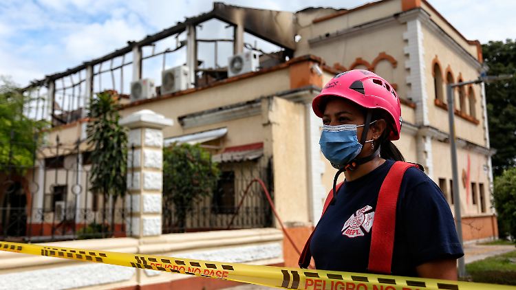 Eine Feuerwehrfrau steht vor dem durch ein Feuer stark beschädigten Justizpalast in Tulua. 