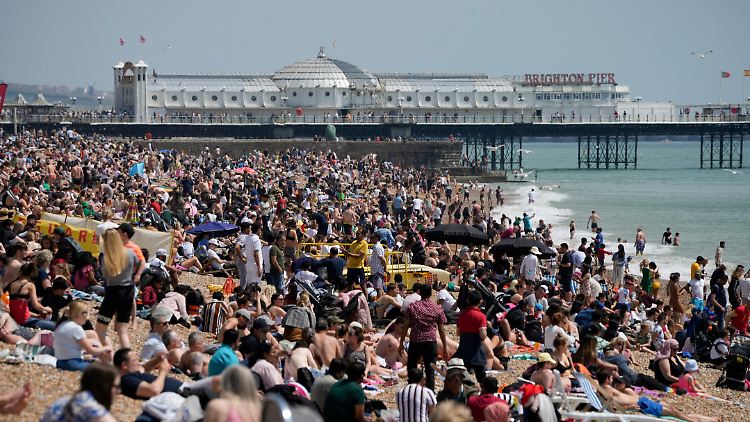 Besucher verbringen bei warmen Temperaturen Zeit am Brighton Beach an der Südküste Großbritanniens.
