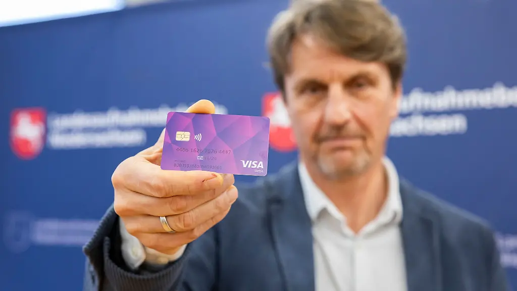 Der-Praesident-der-Landesaufnahmebehoerde-praesentiert-eine-der-ersten-Bezahlkarten-fuer-Gefluechtete