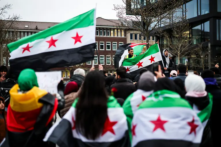 Feiernde-schwenken-die-Flagge-der-syrischen-Revolution-vor-dem-Hauptbahnhof-in-Duisburg-Die-Flagge-der-Gegner-des-Assad-Regimes-zeigt-drei-horizontale-Streifen-einen-gruenen-einen-weissen-und-einen-schwarzen-sowie-drei-rote-Sterne
