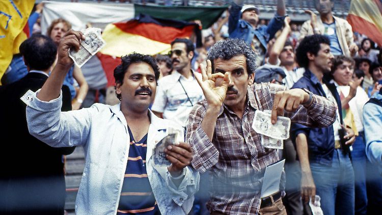 Wütende algerische Fans halten Geldscheine hoch, um den Manipulationsvorwurf gegenüber dem Nichtangriffspakt von Deutschland und Österreich zu demonstrieren.
