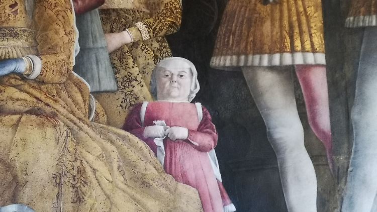 Die kleinwüchsige Frau schaut den Betrachter direkt an.