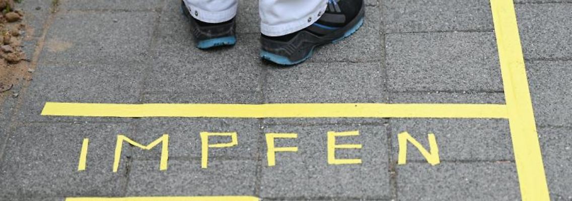 Ein Mann steht an einem Covid-19-Impfcenter hinter der Bodenaufschrift "Impfen". Foto: Arne Dedert/dpa/POOL/dpa/Symbolbild