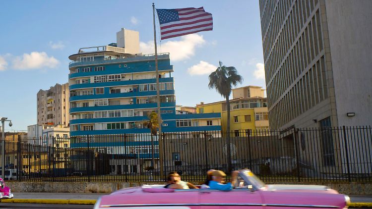 Touristen fahren 2017 in einem Oldtimer vor einer US-Flagge und der US-Botschaft in Havanna vorbei. 