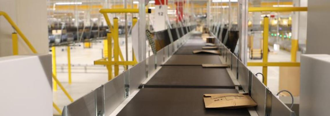 Amazon-Versandkartons liegen auf Transportbändern bei einem Probebetrieb in einer Logistikhalle. Foto: Bodo Schackow/dpa-zentralbild/dpa