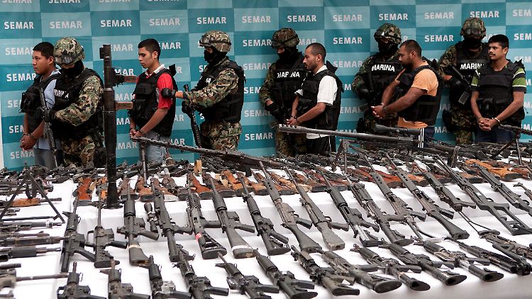 Sichergestellte Waffen und mutmaßliche Mitglieder einer Drogenbande werden in Mexiko-Stadt vorgeführt.