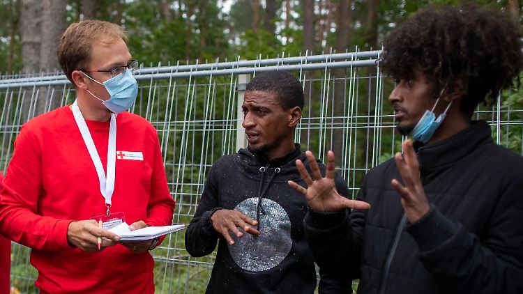 Ein Mitarbeiter des Roten Kreuzes im Gespräch mit Flüchtlingen, die in einem Camp südlich von Vilnius untergebracht sind. 